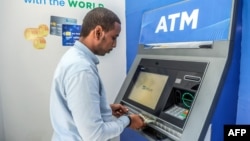 Msomali akitoa pesa kutoka kwenye ATM huko Mogadishu Desemba 14,2023. Picha na Hassan Ali Elmi / AFP.