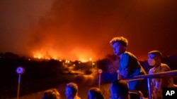 Local residents try to reach their houses in Benijos village as police block the area as fire advances in La Orotava in Tenerife, Canary Islands, Spain, Aug. 19, 2023.