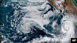 This Aug. 18, 2023, 1:10 p.m. EDT satellite image provided by the National Oceanic and Atmospheric Administration shows Hurricane Hilary, right, off Mexico’s Pacific coast.