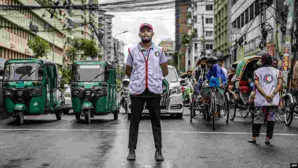 Commuters wait at a road crossing while Bangladeshi students control the traffic as police went on strike in Dhaka.