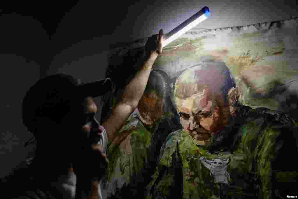 El artista ucraniano Yevhen Klymenko, de 29 años, utiliza una lámpara LED para mostrar un retrato del excomandante en jefe de las Fuerzas Armadas de Ucrania, Valeri Zaluzhny, durante un apagón en Kiev, Ucrania, el 5 de junio de 2024. REUTERS/Alina Smutko