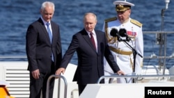 Predsednik Rusije Vladimir Putin, ministar odbrane Andrej Belousov i glavnokomandujući ruske mornarice admiral Aleksandar Mojsejev prisustvuju godišnjoj paradi povodom Dana mornarice u Sankt Peterburgu, 28. jula 2024. (Dmitrij Lovecki/Pool preko Rojtersa)