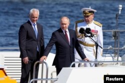 Presiden Rusia Vladimir Putin, Menteri Pertahanan Andrei Belousov, dan Panglima Angkatan Laut Rusia Laksamana Alexander Moiseyev menghadiri parade tahunan Hari Angkatan Laut di Saint Petersburg, 28 Juli 2024. (Foto: via Reuters)