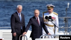 O presidente da Rússia, Vladimir Putin, o ministro da Defesa, Andrei Belousov, e o comandante-chefe da Marinha russa, almirante Alexander Moiseyev, assistem ao desfile anual do Dia da Marinha em São Petersburgo, a 28 de julho de 2024. (Dmitri Lovetsky/Pool via Reuters)