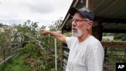 Chuck Ridder, owner of Knox Drive Farm and Feed, points out the uprooted tree that fell on his pens used by local 4H students, along with other impacts of hurricane Beryl on him, his feed store and customers, July 12, 2024, in Porter, Texas.