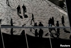 Sosok para pekerja terpantul di jendela gedung perkantoran di kawasan bisnis Barangaroo Sydney, Australia, 8 Mei 2017. (REUTERS/Jason Reed)