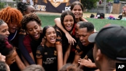 Young women and their coach Dioguinho bring it in for a team huddle at the start of a football training session run by the Bola de Ouro social program, at the Complexo da Alemao favela in Rio de Janeiro, Brazil, May 16, 2024. 