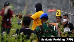 Seorang tersangka saat melakukan rekonstruksi di Mimika pada 3 September 2022, setelah dia dan lima tentara ainnya didakwa atas tuduhan pembunuhan terhadap empat warga asli Papua dan memutilasi tubuh mereka. (Foto: AFP/Sevianto Pakiding)