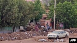 People sit near a trench in Khartoum, Sudan, amid ongoing fighting between the forces of two rival generals, on May 11, 2023.