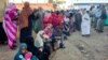 FILE - People from states of Khartoum and al-Jazira, displaced by the ongoing conflict in Sudan between the army and paramilitaries, wait to receive aid from a charity organization in Gedaref on December 30, 2023.