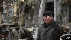A man takes a video of a damaged restaurant after Russian shelling hit in Zaporizhzhia, Ukraine, March 18, 2023.