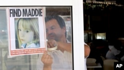 FILE - A waiter hangs a picture of missing 3-year-old Madeleine McCann on a restaurant's window, May 10 2007, in Praia da Luz, southern Portugal. 