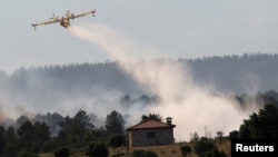 A firefighting plane dumps water as a wildfire burns, in Hernan-Perez, Estremadura, Spain, May 19, 2023. 
