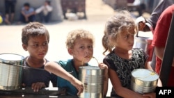 Children wait for food being distributed at a camp for internally displaced people where they live due to the Israeli bombardment of the Gaza Strip, in Khan Younis in the southern Gaza Strip, June 11, 2024, 