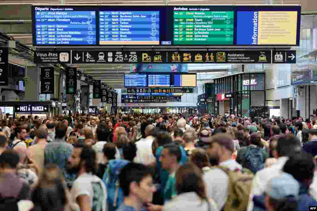 Passengers gather around departure and arrival boards at the Gare Montparnasse train station in Paris as France&#39;s high-speed rail network was hit by malicious acts disrupting the transport system hours before the opening ceremony of the Paris 2024 Olympic Games.