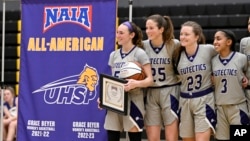 FILE - NAIA women’s basketball players gather after a game in St. Louis, Feb. 22, 2024. The National Association of Intercollegiate Athletics, the governing body for mostly small colleges, said Monday that transgender athletes would be all but banned from women's sports.