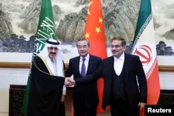 2023年3月10日，伊朗最高國家安全委員會秘書阿里·沙姆哈尼(Ali Shamkhani)（右）在北京舉行會談時同沙特國務大臣、內閣成員和國家安全顧問穆薩伊德·本·穆罕默德·艾班握手， 中共中央政治局委員、中央外辦主任王毅居中。