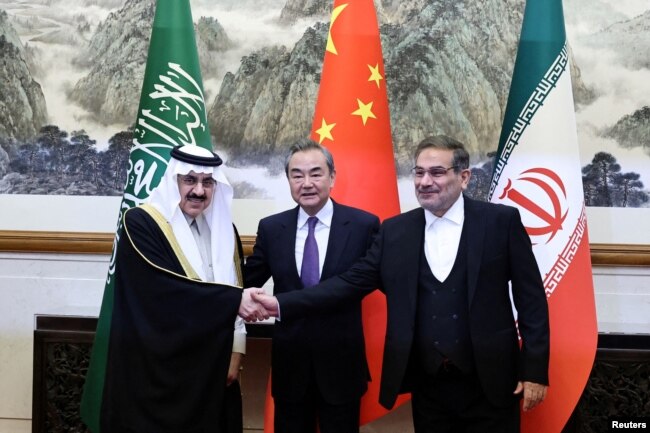 2023年3月10日，伊朗最高国家安全委员会秘书阿里·沙姆哈尼(Ali Shamkhani)（右）在北京举行会谈时同沙特国务大臣、内阁成员和国家安全顾问穆萨伊德·本·穆罕默德·艾班握手， 中共中央政治局委员、中央外办主任王毅居中。