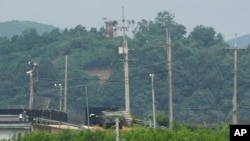 Pos penjagaan militer Korea Utara tampak berada di atas sementara kendaraan militer Korea Selatan bergerak di area bawah di wilaya Paju, Korea Selatan, dekat perbatasan kedua negara pada 21 Juli 2024. (Foto: AP/Ahn Young-joon)