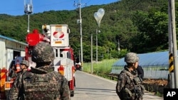 FILE - In this photo provided by Jeonbuk Fire Headquarters, balloons with trash presumably sent by North Korea hang on electric wires as South Korean army soldiers stand guard in Muju, South Korea, May 29, 2024.