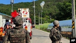 FILE - In this photo provided by Jeonbuk Fire Headquarters, balloons with trash presumably sent by North Korea hang on electric wires as South Korean army soldiers stand guard in Muju, South Korea, May 29, 2024.