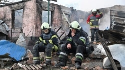 Petugas pemadam kebakaran beristirahat setelah memadamkan api di sebuah rumah pribadi yang hancur akibat serangan drone Rusia di pinggiran kota Kharkiv, pada 21 Mei 2024. (Foto: AFP)