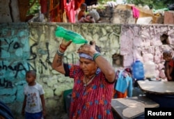 แฟ้มภาพ - สตรีคนหนึ่งราดน้ำลงบนศีรษะในวันอากาศร้อน ในกรุงนิวเดลี ประเทศอินเดีย เมื่อ 21 พ.ค. 2567