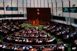 Anggota parlemen angkat tangan untuk memilih usai pembacaan kedua undang-undang Undang-Undang Dasar Pasal 23 di Dewan Legislatif di Hong Kong, Selasa, 19 Maret 2024. (Foto: AP)