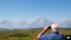 FILE - Steve Carringer of Tennessee takes a photo of the mountains at Jackson Lake Lodge, the site of the Jackson Hole Economic Symposium, in Grand Teton National Park near Moran, Wyo., Aug. 22, 2024. 