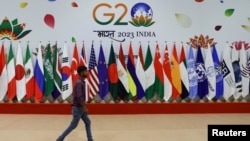 A man walks past flags set up for the G20 Summit in New Delhi, Sept. 8, 2023.