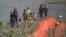 FILE - Migrants trying to enter the US from Mexico approach the site where workers are assembling large buoys to be used as a border barrier along the banks of the Rio Grande in Eagle Pass, Texas, July 11, 2023. 
