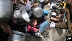Warga Palestina menerima bantuan selama serangan Israel di Jalur Gaza di Rafah, 9 Januari 2024. Pasokan makanan kini terancam, dan mereka yang mengungsi akibat serangan tersebut menghadapi krisis kesehatan masyarakat, kata seorang pejabat senior PBB pada 14 Juni 2024. (Foto: AP)