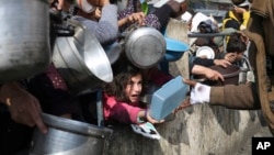 FILE - Palestinians receive aid during the Israeli offensive on the Gaza Strip in Rafah, Jan. 9, 2024. Supplies of food are now at risk, and those displaced by the offensive face a public health crisis, a senior U.N. official said June 14, 2024.