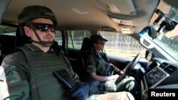 FILE - A member of the Lithuanian Riflemen's Union and a Border Guard officer patrol along the border with Belarus in Kaniukai, Lithuania, July 7, 2023. 