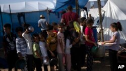 Children wait in line for a food distribution in a tent camp for the displaced, in Khan Younis, southern Gaza Strip, Oct. 25, 2023.