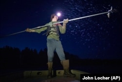 Gabe Bisonette, a member of the Lac Courte Oreilles Band of Lake Superior Ojibwe, spears a walleye by headlamp on the Chippewa Flowage Monday, April 15, 2024, near Hayward, Wis. (AP Photo/John Locher)