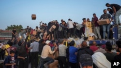 Palestinians storm trucks loaded with humanitarian aid brought in through a new U.S.-built pier in the central Gaza Strip, May 18, 2024.