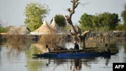 FILE: Women transport firewood through flood water in Bentiu on February 6, 2023. - Four straight years of flooding has swamped two-thirds of South Sudan but nowhere more dramatically than Bentiu, a northern city besieged by water.