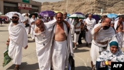 A man effected by the scorching heat is helped by another as Muslim pilgrims arrive to perform the symbolic "stoning of the devil" ritual as part of the Hajj pilgrimage in Mina, near Saudi Arabia's holy city of Mecca, on June 16, 2024.