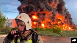 Photo released by the Governor of Sevastopol Mikhail Razvozhaev on April 29, 2023, a firefighter speaks on the walkie talkie near a burning fuel tank in Sevastopol, Crimea.