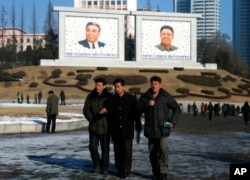 资料照片：朝鲜男子在平壤走过已故领导人金日成和金正日父子的巨大肖像。 (2018年12月18日)