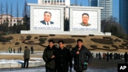 FILE - North Korean men walk past portraits of their late leaders Kim Il Sung and his son Kim Jong Il in Pyongyang, North Korea, Dec. 18, 2018.