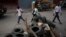 FILE - People pass a barricade that closes the entrance for vehicles after 6 p.m. erected by the Bwa Kale movement, an initiative to fight gangs seeking to take control of the neighborhood, in the Canape Vert area of Port-au-Prince, Haiti, May 31, 2023.