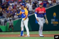 David Peralta (6) de Venezuela celebra después de anotar un doblete de Eugenio Suárez mientras el tercera base de República Dominicana, Manny Machado, observa durante la sexta entrada de un juego del Clásico Mundial de Béisbol, el sábado 11 de marzo de 2023, en Miami. (Foto AP/Wilfredo Lee)