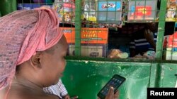 FILE - Kenyan housekeeper Brenda Vitute checks her mobile money wallet at an M-Pesa booth in Nairobi, Kenya on May 25, 2022. Thomson Reuters Foundation/Nita Bhalla