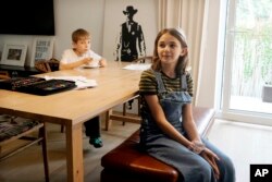 Ola Kozak, 11, kanan, dan adik laki-lakinya Julian Kozak, 9, duduk di meja tempat mereka biasa mengerjakan pekerjaan rumah di rumah keluarga di Warsawa, Polandia, Jumat, 5 April 2024. ( AP/Czarek Sokolowski)