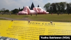 Para pengunjung sedang berfoto di sekitar boneka balon raksasa berbentuk kelinci berwarna merah muda karya pekerja seni asal AS, KAWS, di Candi Prambanan, Sleman, Yogyakarta, Kamis, 24 Agustus 2023. (Foto: Yudha Satriawan/VOA)