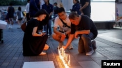 几名游客在泰国曼谷的暹罗百丽宫购物中心外摆放蜡烛。该购物中心发生了致人丧生的枪击事件。（2023年10月4日）