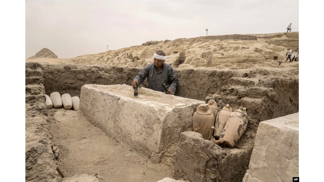 Seorang pekerja barang antik Mesir menyikat alas pembalseman yang baru saja digali di lokasi Piramida Langkah Djoser di Saqqara, 24 kilometer barat daya Kairo, Mesir, 27 Mei 2023. (Foto: AP)