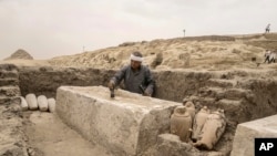 An Egyptian antiquities worker brushes a recently unearthed embalming bed at the site of the Step Pyramid of Djoser in Saqqara, 24 kilometers (15 miles) southwest of Cairo, Egypt, May 27, 2023.